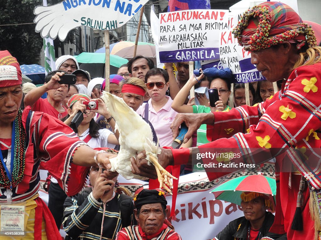 Indigenous peoples from Mindanao slit a chicken's neck to...
