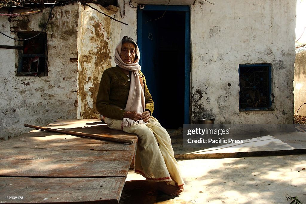 An elderly Nepalese widow sits in front of her small living...