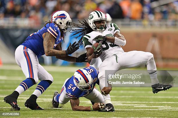 Chris Ivory of the New York Jets is tackled by Larry Dean and Brandon Spikes of the Buffalo Bills in the fourth quarter at Ford Field on November 24,...