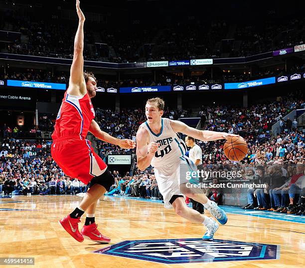 Cody Zeller of the Charlotte Hornets drives against Spencer Hawes of the Los Angeles Clippers on November 24, 2014 at Time Warner Cable Arena in...
