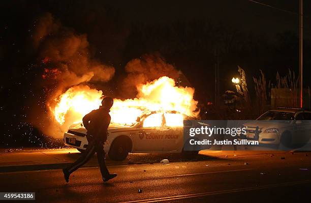 Police officer runs by a burning police car during a demonstration on November 24, 2014 in Ferguson, Missouri. A St. Louis County grand jury has...