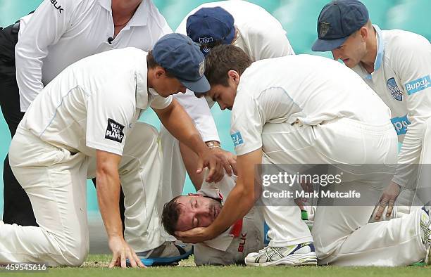 Phillip Hughes of South Australia is helped by New South Wales players after falling to the ground after being struck in the head by a delivery...