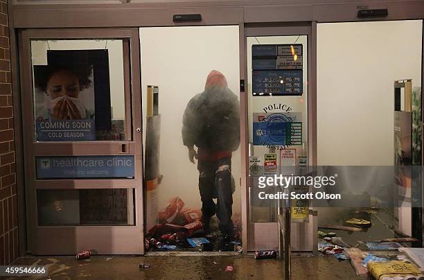 Looter walks out of a burning Walgreens store which was set on fire after protestors rioted following the grand jury announcement in the Michael...