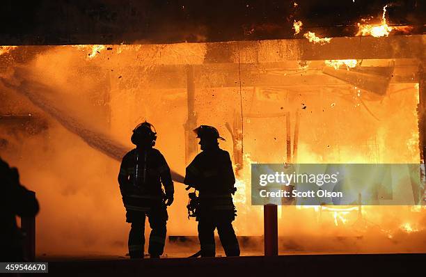 Firefighters try to extinguish a burning restaurant set on fire after protestors rioted following the grand jury announcement in the Michael Brown...