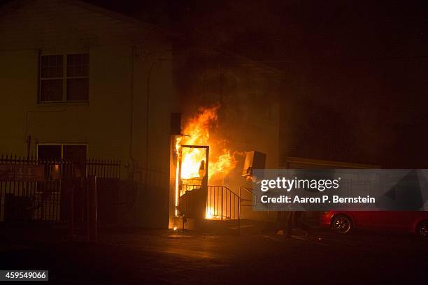 Looter throws items into a burning business during rioting on November 24, 2014 in Ferguson, Missouri. A St. Louis County grand jury has declined to...