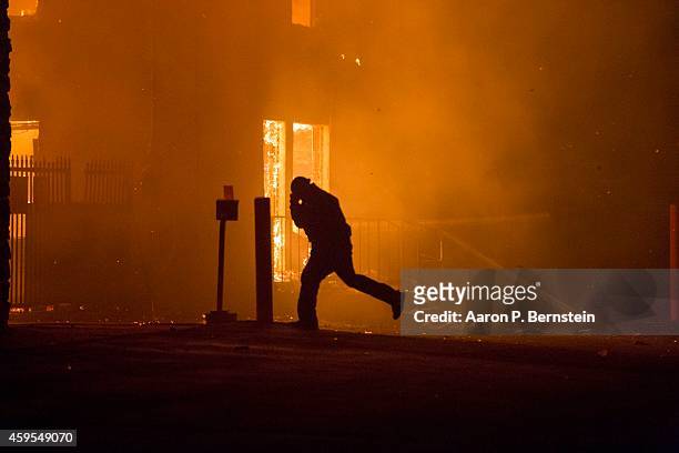 Protester runs in front of a burning business during rioting on November 25, 2014 in Ferguson, Missouri. A St. Louis County grand jury has declined...