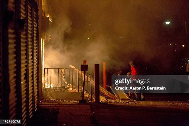 Looters throw items into a burning business during rioting on November 24, 2014 in Ferguson, Missouri. A St. Louis County grand jury has declined to...