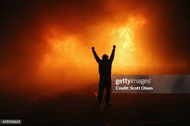 Demonstrator celebrates as a business burns after it was set on fire during rioting following the grand jury announcement in the Michael Brown case...