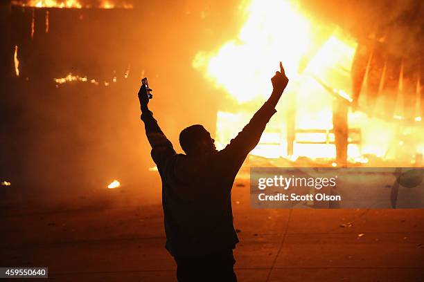 Demonstrator celebrates as a business burns after it was set on fire during rioting following the grand jury announcement in the Michael Brown case...