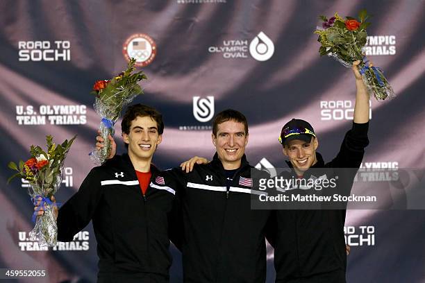 Emery Lehman, Jonathan Kuck and Patrick Meek celebrate on the medals podium after the men's 5,000 meter during the Long Track Olympic Trials at the...