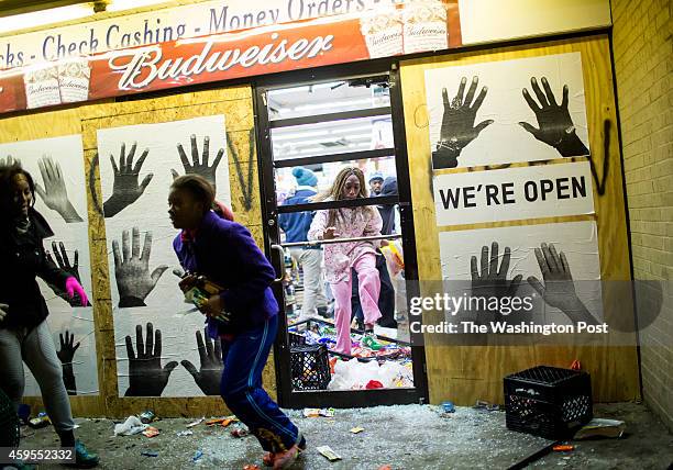 People leave a liquor store with items after protestors rioted following the grand jury announcement in the Michael Brown case on November 24, 2014...