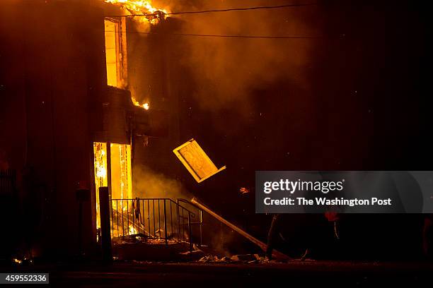 Protestor throws wood onto a burning storage business after protestors rioted following the grand jury announcement in the Michael Brown case on...