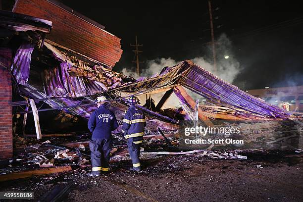 Ferguson firefighters survey rubble at a strip mall that was set on fire when rioting erupted following the grand jury announcement in the Michael...