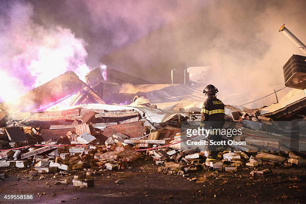 Ferguson firefighter surveys damage to a strip mall that was set on fire when rioting erupted following the grand jury announcement in the Michael...