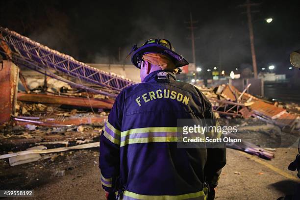 Ferguson firefighter surveys rubble at a strip mall that was set on fire when rioting erupted following the grand jury announcement in the Michael...