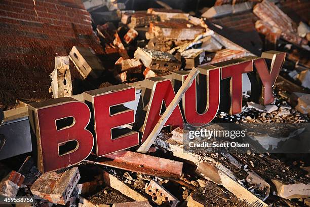 Sign rests in the rubble of a strip mall that was set on fire when rioting erupted following the grand jury announcement in the Michael Brown case on...