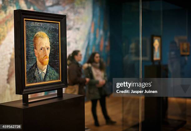 Visitors look at a self portraits of Dutch Post-Impressionist painter Vincent van Gogh on the ground floor of the Vincent van Gogh museum on November...