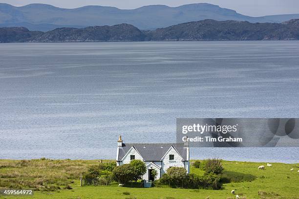 Traditional Scottish farmhouse home and farm on Wester Ross coastal trail near Applecross, in North West Coast of Scotland. Behind is Isle of Raasay...