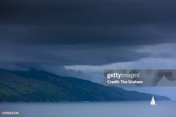 Yacht with white sails in moody serene atmospheric scene as Sound of Mull joins Firth of Lorn on the West Coast of Scotland