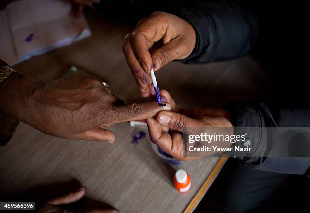 An official marks a finger of a Kashmiri woman before casting her vote inside the polling station during the first phase of assembly elections on...