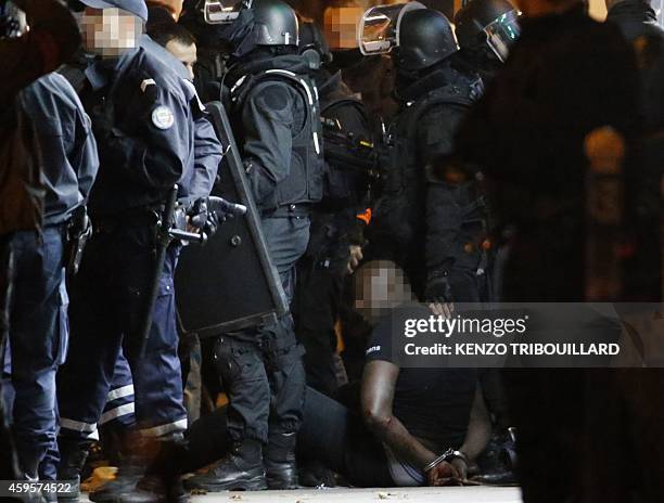 One of the two alleged robbers who attempted to rob a Cartier jewellery store on the Champs-Elysees sits on the ground after surrendering to French...