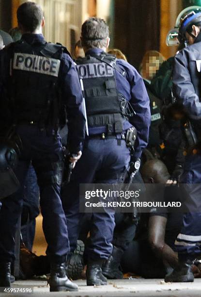 One of the two alleged robbers who targeted a Cartier jewellery store on the Champs-Elysees sits on the ground after surrendering to French police...