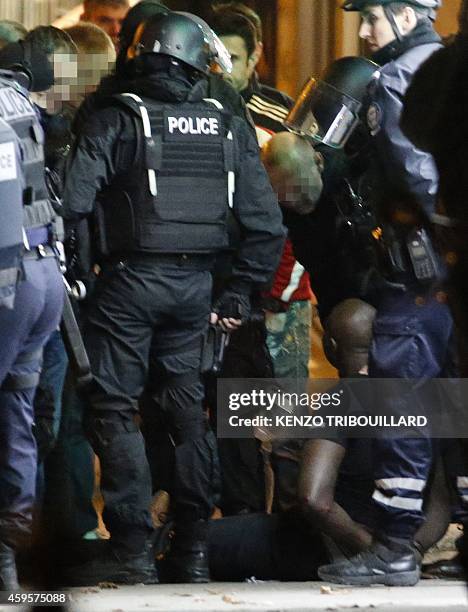 One of the two alleged robbers who attempted to rob a Cartier jewellery store on the Champs-Elysees sits on the ground after surrendering to French...