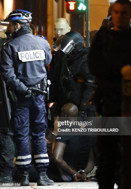 One of the two alleged robbers who targeted a Cartier jewellery store on the Champs-Elysees sits on the ground after surrendering to French police...