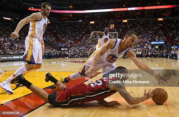 Shabazz Napier of the Miami Heat and Stephen Curry of the Golden State Warriors fight for a loose ball during a game at American Airlines Arena on...