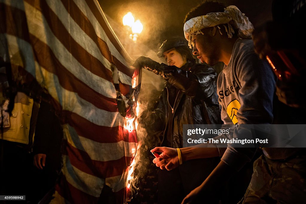 Protesters burn a US flag as they march through downtown Washington, DC following a Missouri grand jury's decision not to indict Officer Darren Wilson in Washington...