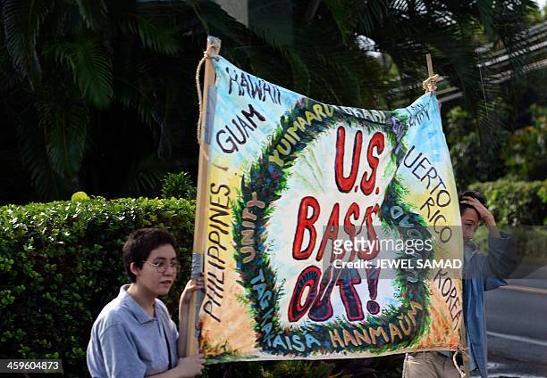 Group of protesters show placards as US President Barack Obama's motorcade arrives at his vacation home in Kailua, Hawaii, on December 28, 2013. The...