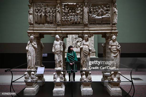 An employee poses next to an exhibit entitled 'Tomb of St Peter Martyr' by Giovanni di Balduccio and dated 1338 during a press preview for the newly...