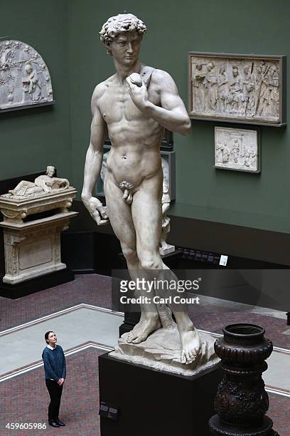 An employee poses next to a five metre high cast of Michelangelo's David during a press preview for the newly renovated Weston Cast Court at the...