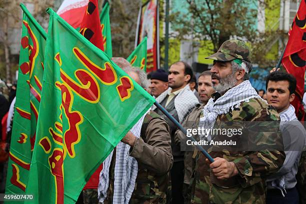 Iranian men hold flags during the celebrations marking the 35th anniversary of the Basij , a paramilitary volunteer militia established in 1979 by...