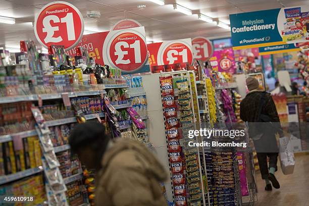 Red one pound signs stand above a tinned food and confectionary display aisle inside a Poundland discount store, operated by Poundland Group Plc, in...