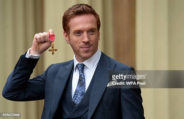 Actor Damian Lewis holds his Officer of the Order of the British Empire after the Investiture ceremony at Buckingham Palace on November 26, 2014...