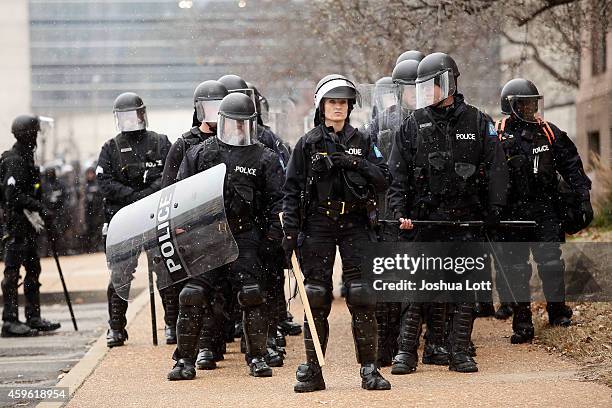 Police officers in riot gear stand outside city hall as demonstrators protest the shooting death of Michael Brown November 26, 2014 in St. Louis,...