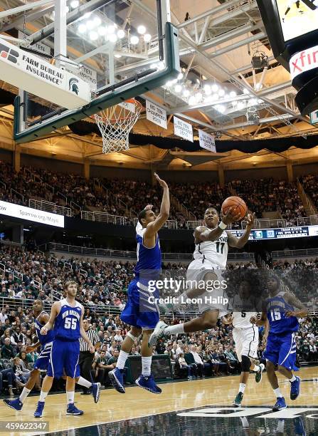 Keith Appling of the Michigan State Spartans drives the ball to the basket during the first half of the game as Tevin Broyles of the New Orleans...