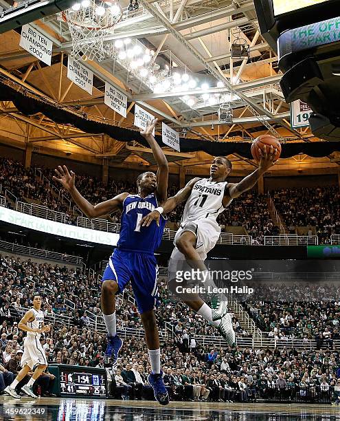 Keith Appling of the Michigan State Spartans drives the ball to the basket during the first half of the game as Tevin Broyles of the New Orleans...