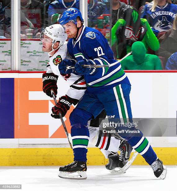 Daniel Sedin of the Vancouver Canucks checks Jonathan Toews of the Chicago Blackhawks during their NHL game at Rogers Arena November 23, 2014 in...