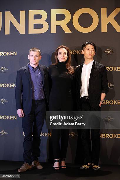 Jack O'Connell, Angelina Jolie and Miyavi pose at a photocall for the film 'Unbroken' on November 27, 2014 in Berlin, Germany.