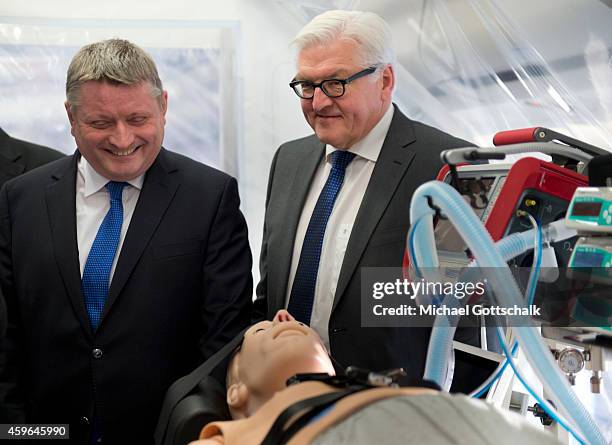 German Health Minister Hermann Groehe and German Foreign Minister Frank-Walter Steinmeier stand next to a mannequin inside an isolation room in the...