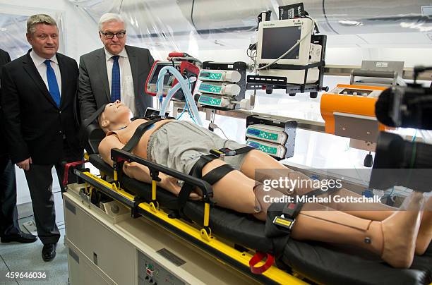 German Health Minister Hermann Groehe and German Foreign Minister Frank-Walter Steinmeier stand next to a mannequin inside an isolation room in the...