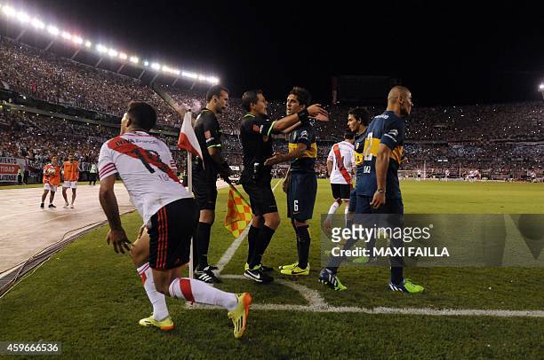 Referee German Delfino gestures with Boca Juniors' defender Juan Forlin and Daniel Diaz during a Copa Sudamericana semifinal soccer against River...