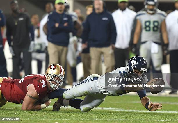 Russell Wilson of the Seattle Seahawks dives to make the line of scrimmage against the tackle of Justin Smith of the San Francisco 49ers in the...