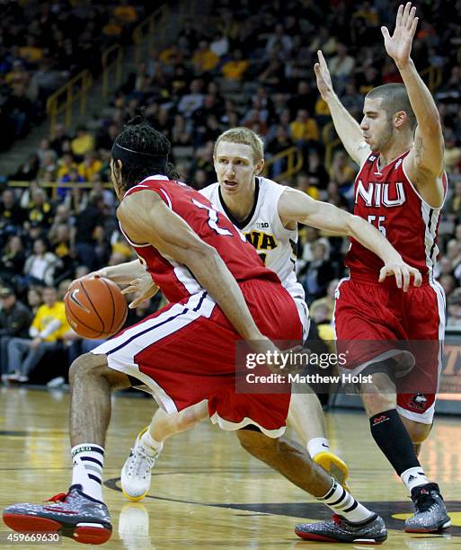 Guard Mike Gesell of the Iowa Hawkeyes brings the ball down the court between guards Michael Orris and Aaric Armstead of the Northern Illinois...