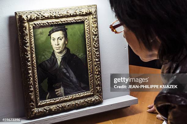 Woman looks at a painting by France's Corneille "Homme au beret noir tenant une paire de gants" displayed on November 27, 2014 at the Musee des Beaux...