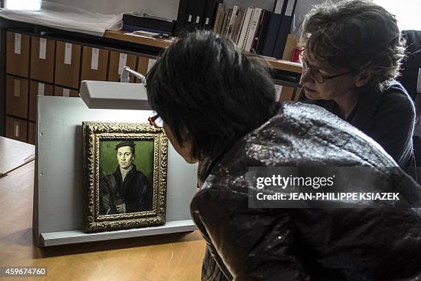 People look at a painting by France's Corneille "Homme au beret noir tenant une paire de gants" displayed on November 27, 2014 at the Musee des Beaux...