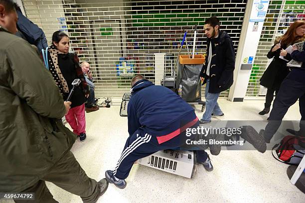 Customers fall to the floor as they grapple for an LED television during a Black Friday discount sale at an Asda supermarket, operated by Wal-Mart...