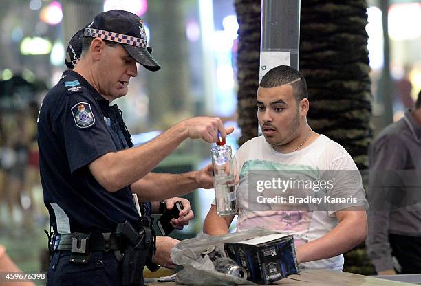 Young man is questioned and his bag searched by police during Australian 'schoolies' celebrations following the end of the year 12 exams on November...